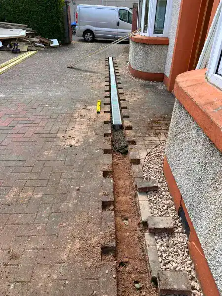 Linear channel drain being installed beside a driveway