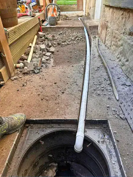 Drain rod being fed into an open manhole