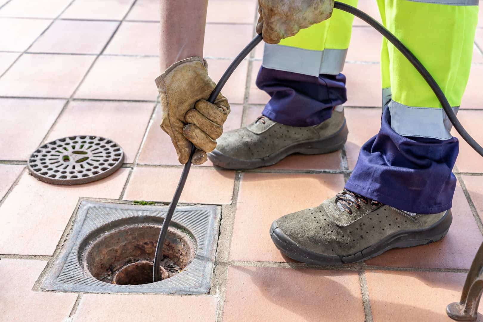 Drainage engineer clearing an outdoor drain with rods